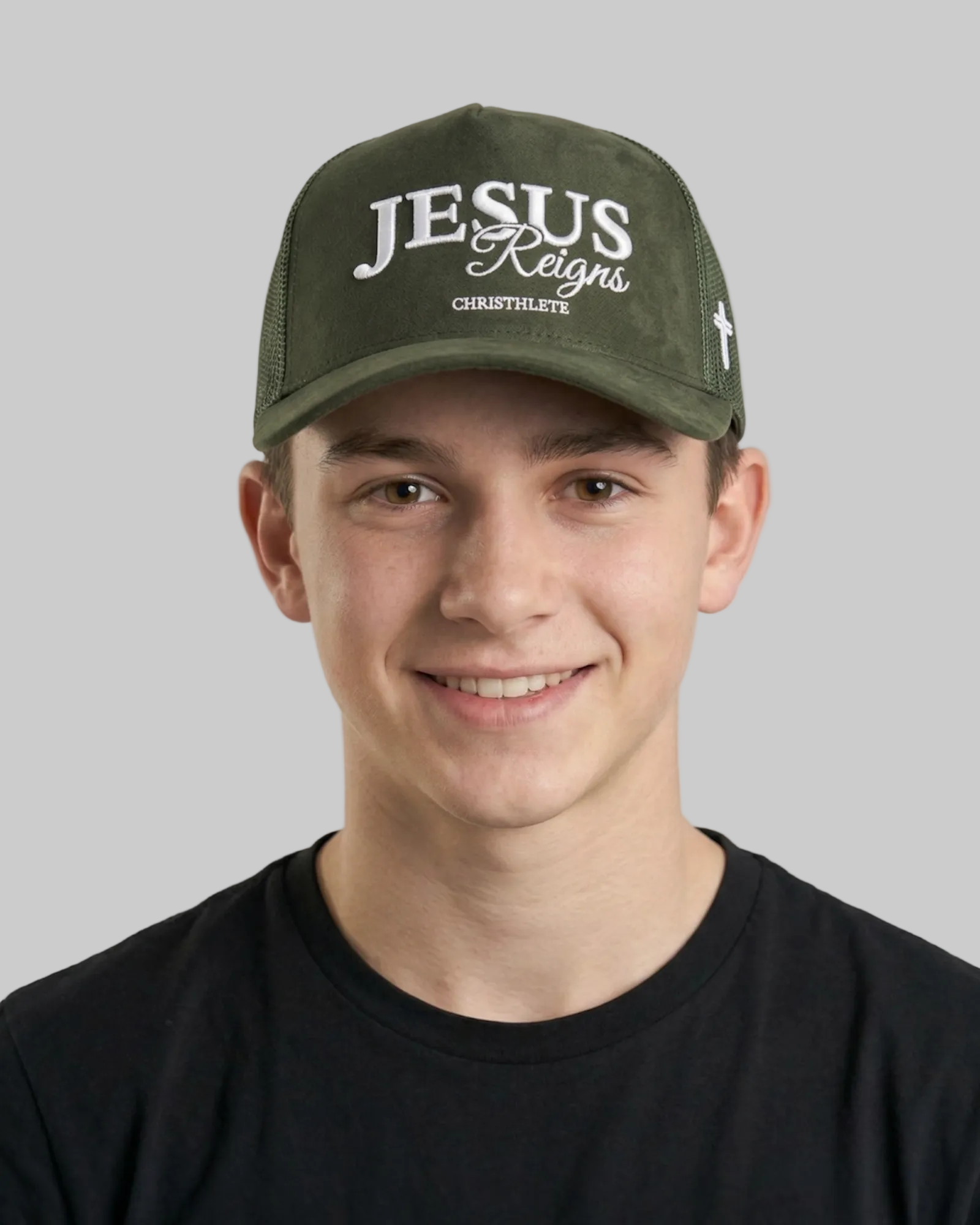 Image of Person wearing a green cap with 'Jesus Reigns' text on a plain background