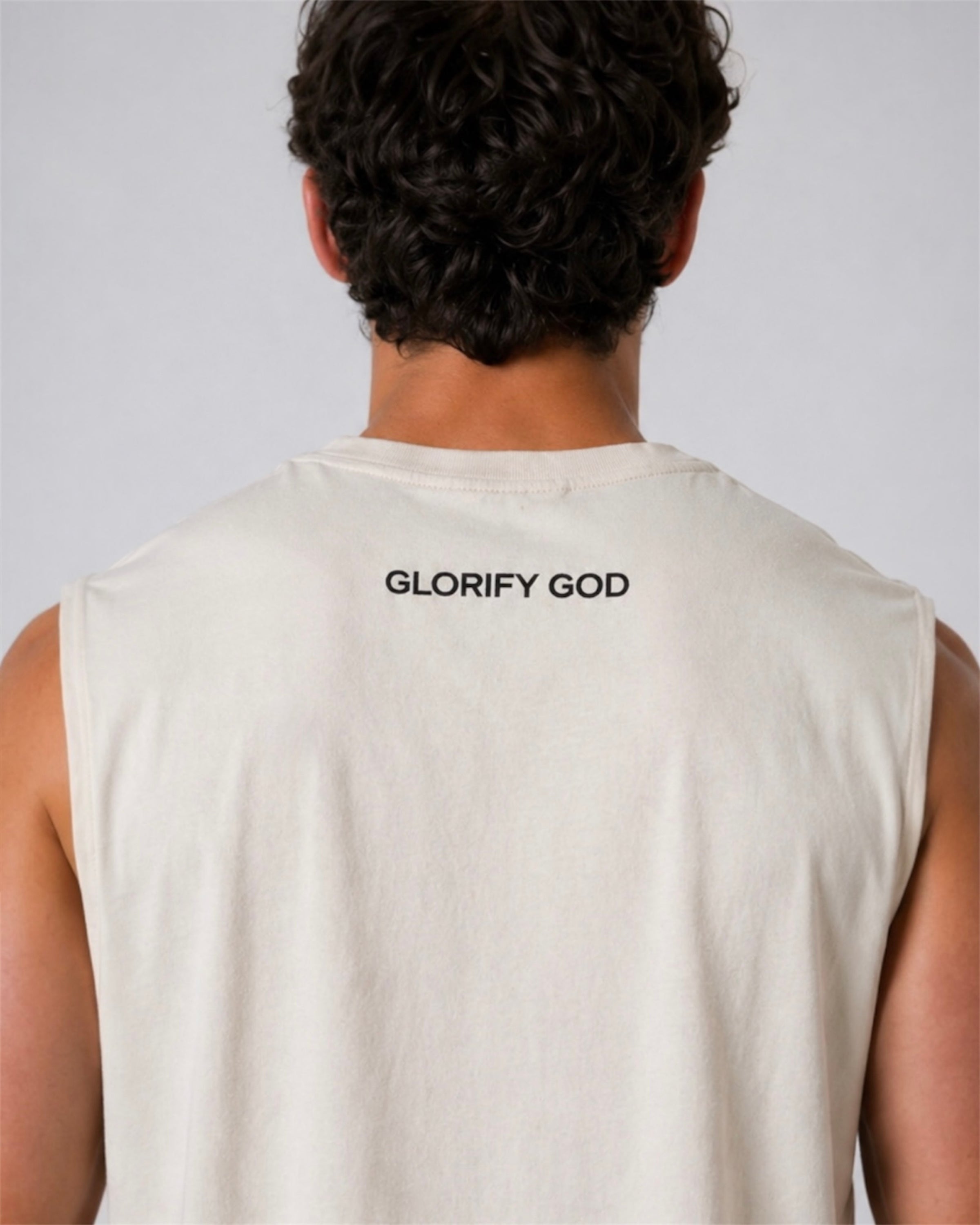 Image of Person wearing a beige sleeveless shirt with 'GLORIFY GOD' text on the back against a plain background