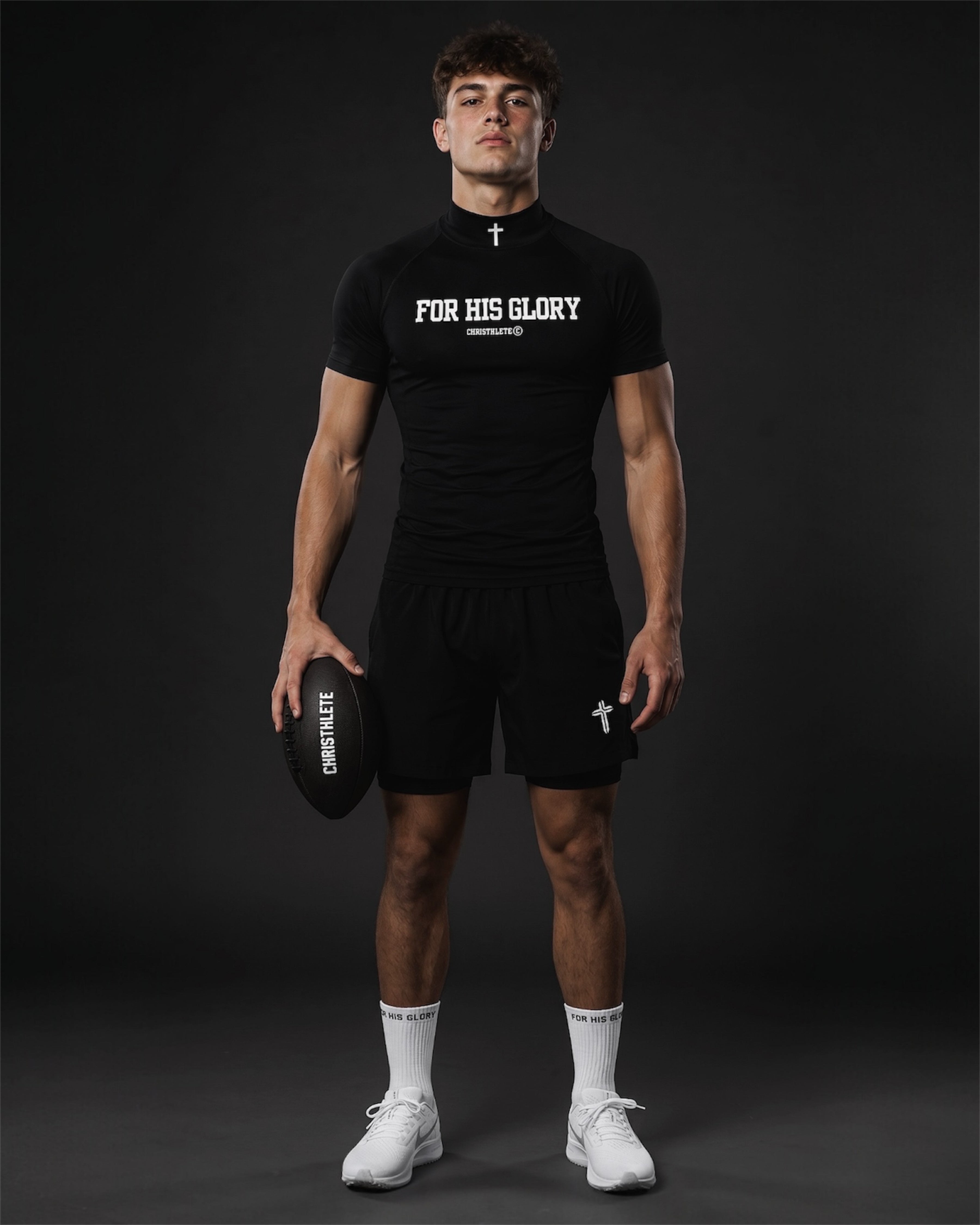 Image of Man wearing a black 'For His Glory' t-shirt and shorts holding a football on a dark background