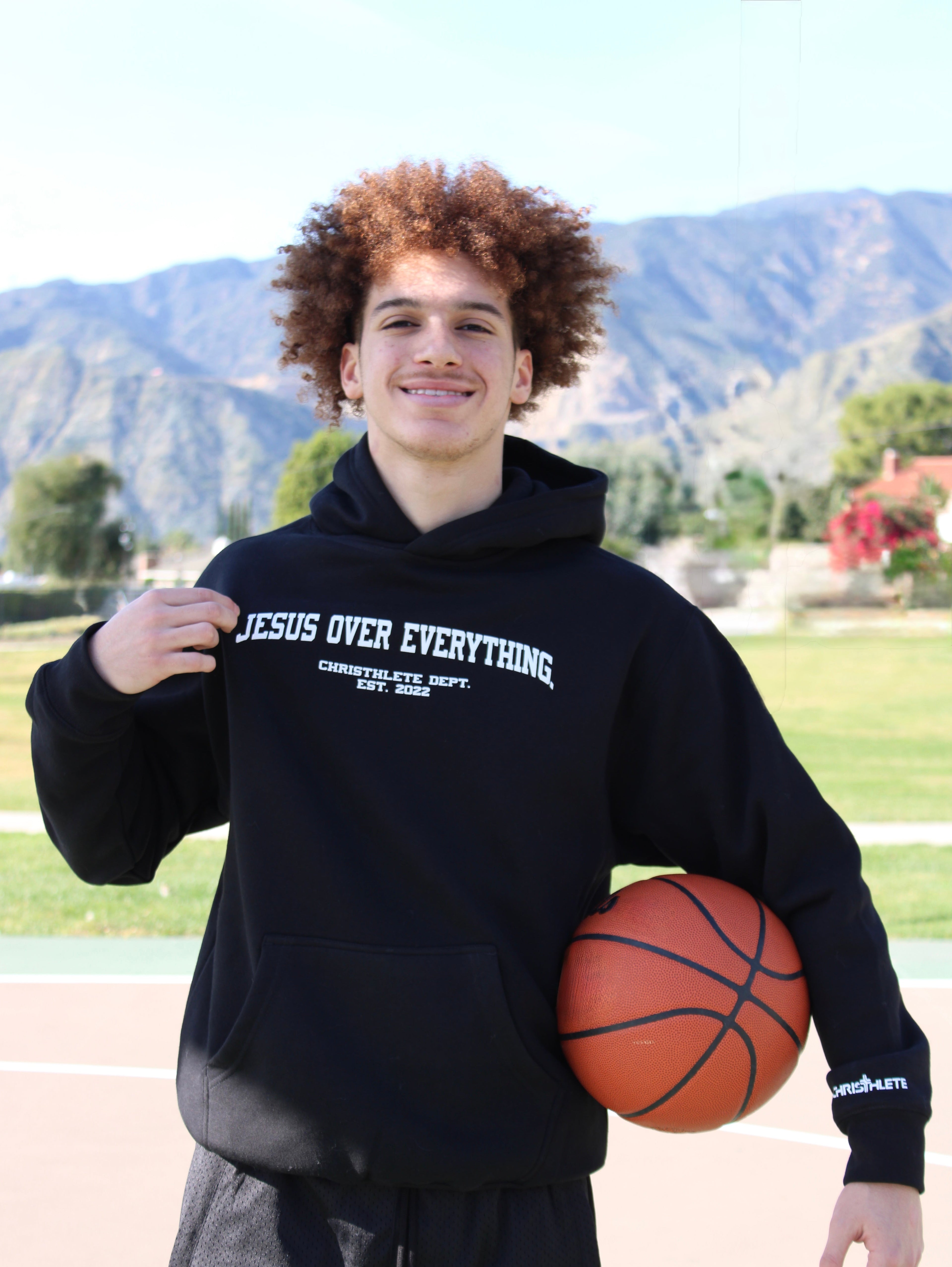 A christian athlete wearing a black hoodie with the writing Jesus Over Everything