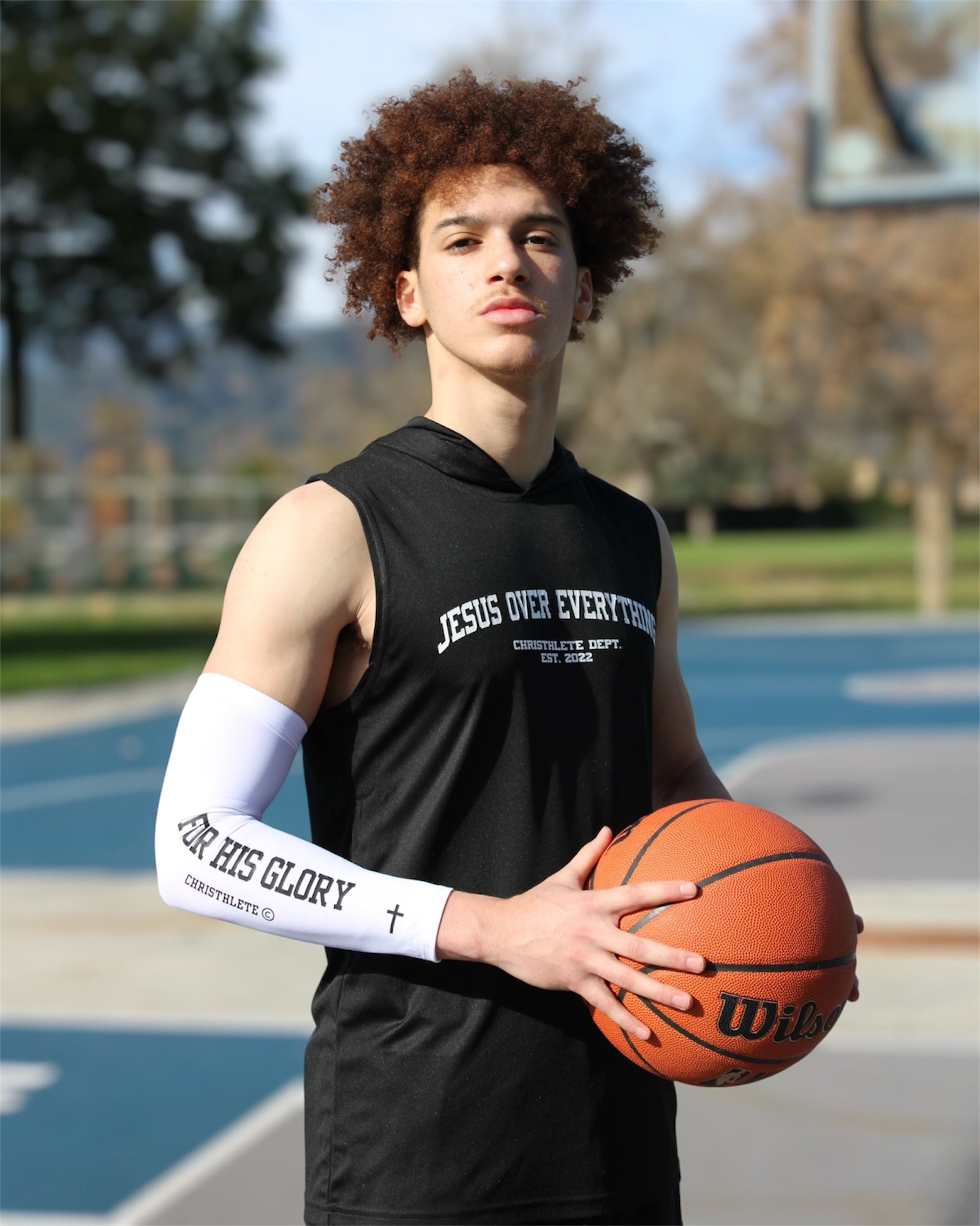 Image of Person holding a basketball on a court with 'Jesus Over Everything' shirt