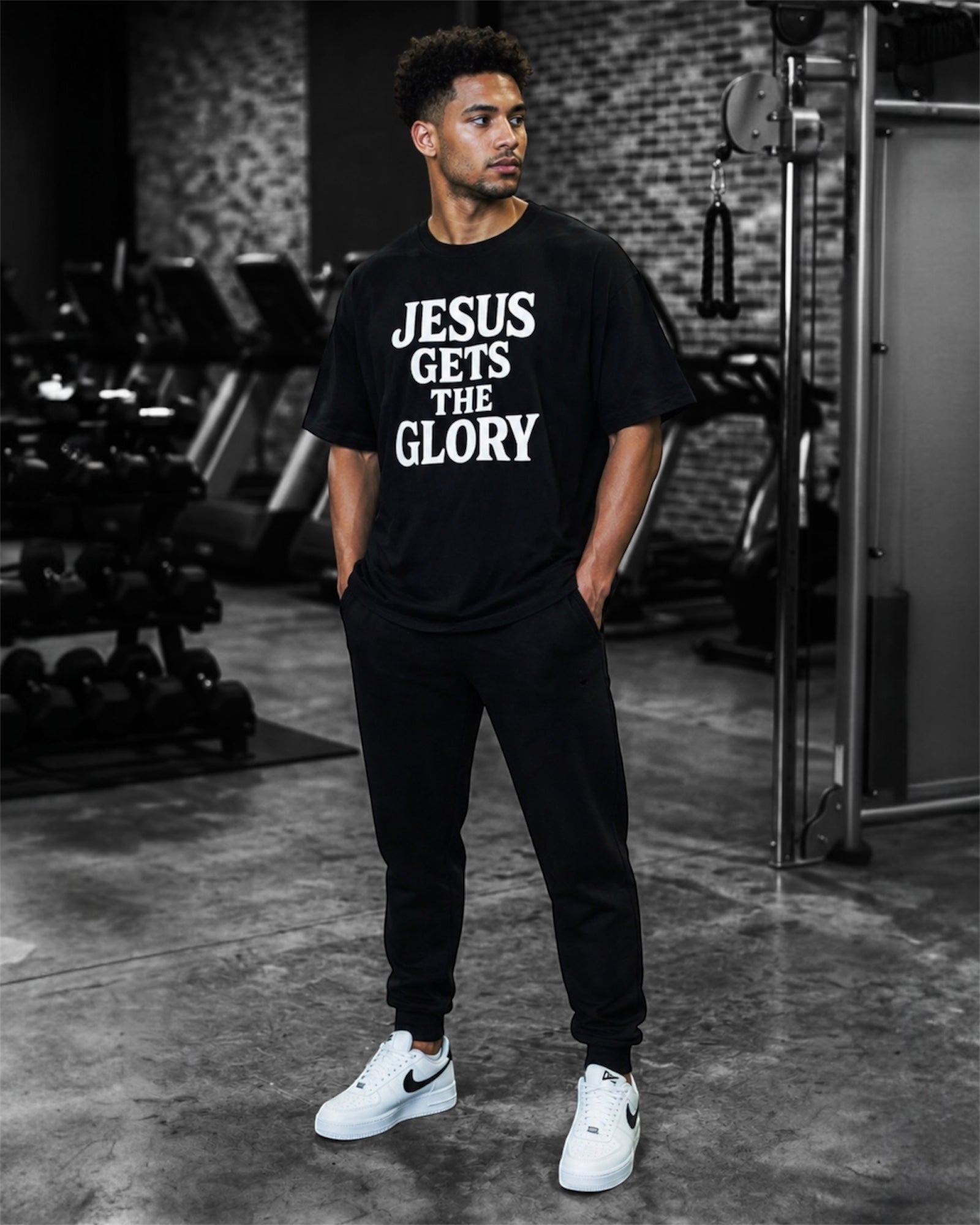 Image of Person wearing a black t-shirt with 'Jesus Gets the Glory' text in a gym setting