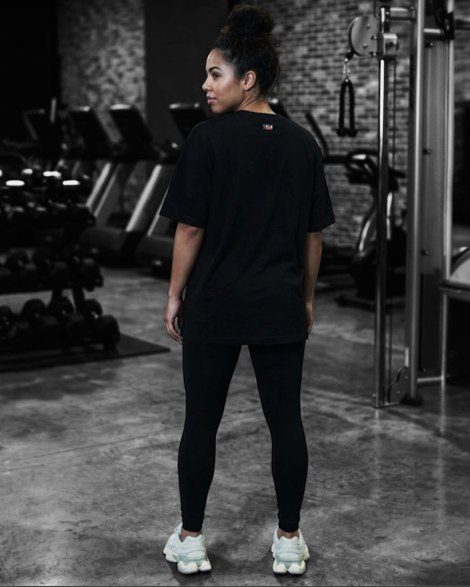 Image of Person wearing a black t-shirt and leggings in a gym setting