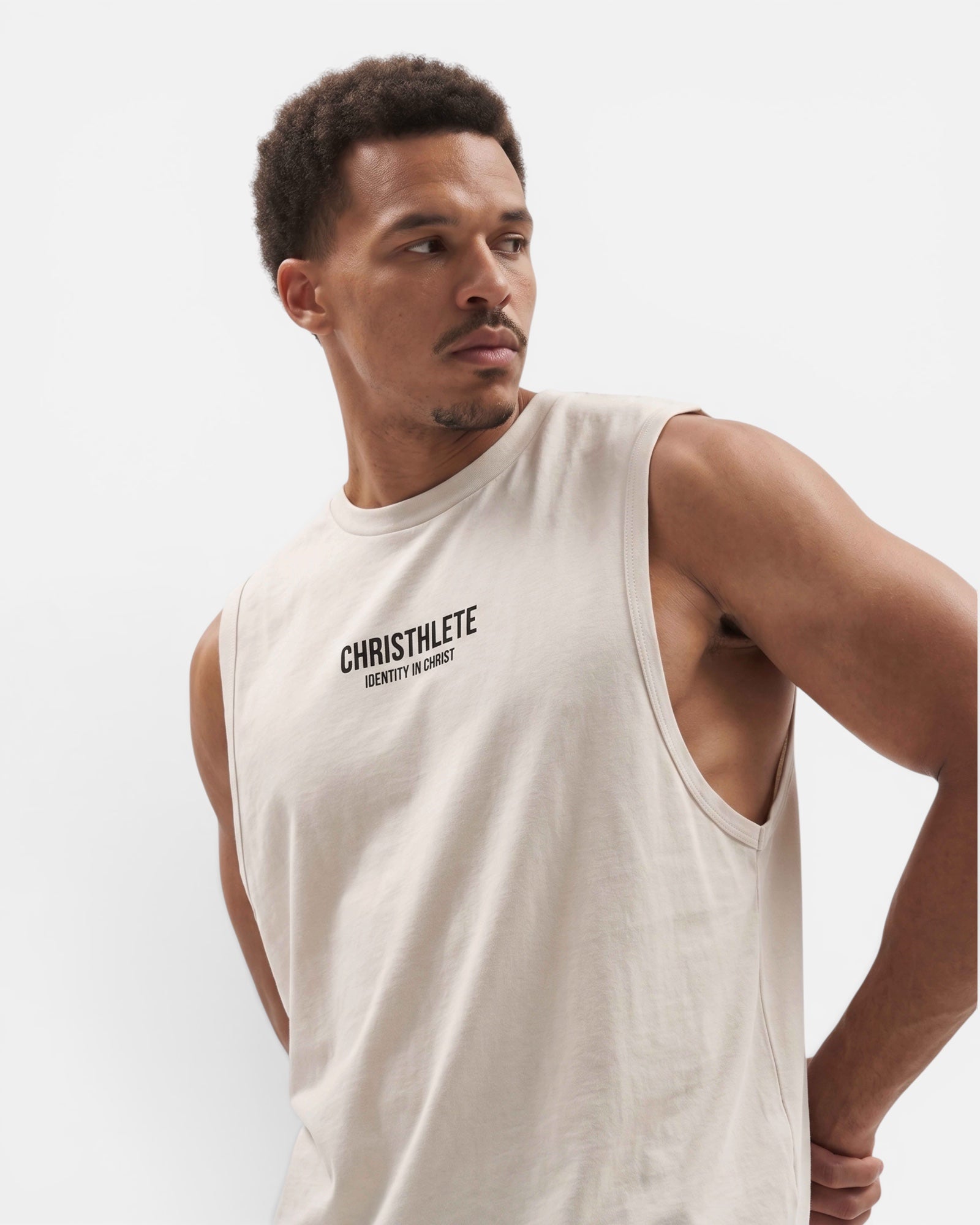 Image of Man wearing a beige sleeveless shirt with 'CHRISTHLETE' logo on a light gray background